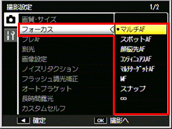 撮影設定メニューで、ADJ./OK ボタンを上下に押し［ フォーカス ］を選び、ADJ./OK ボタンを右に押します